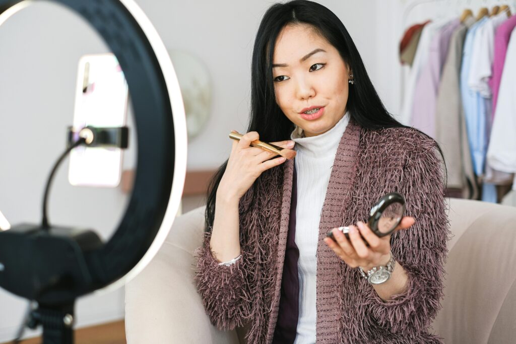 Beauty vlogger demonstrating makeup tips using a ring light during live stream.